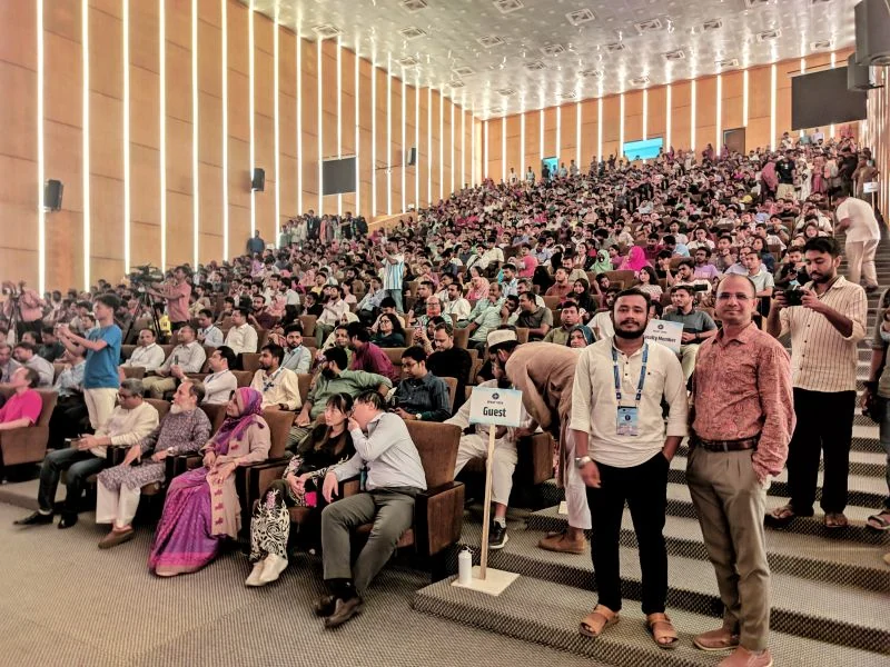 A large tiered auditorium full of conference participants and guests