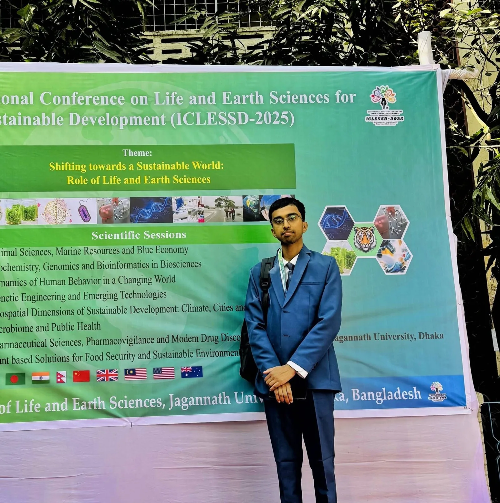 Md Sabbir Islam in a blue suit in front of the ICLESSD-2025 conference banner at Jagannath University