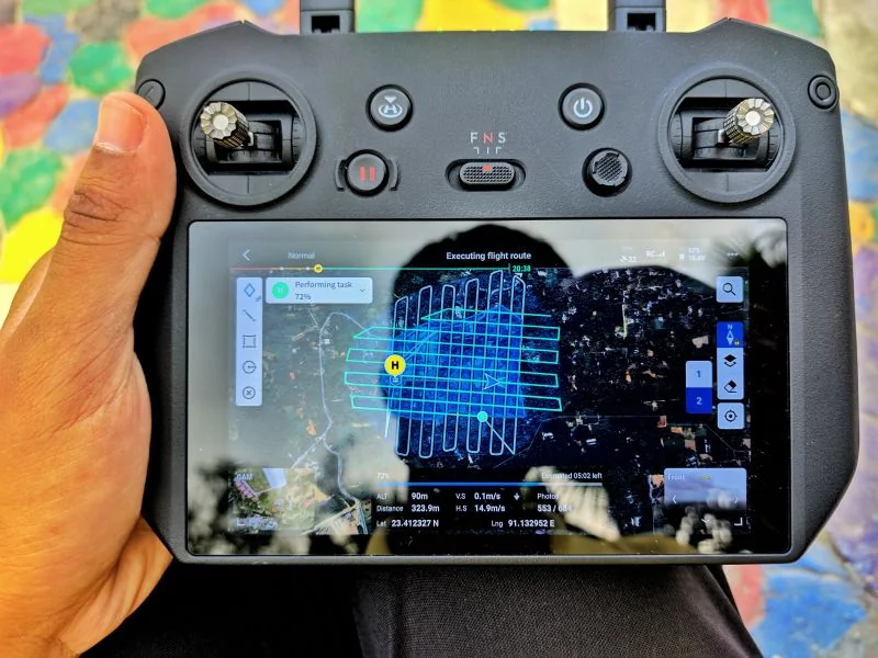 A drone remote controller screen showing a grid flight route over satellite imagery