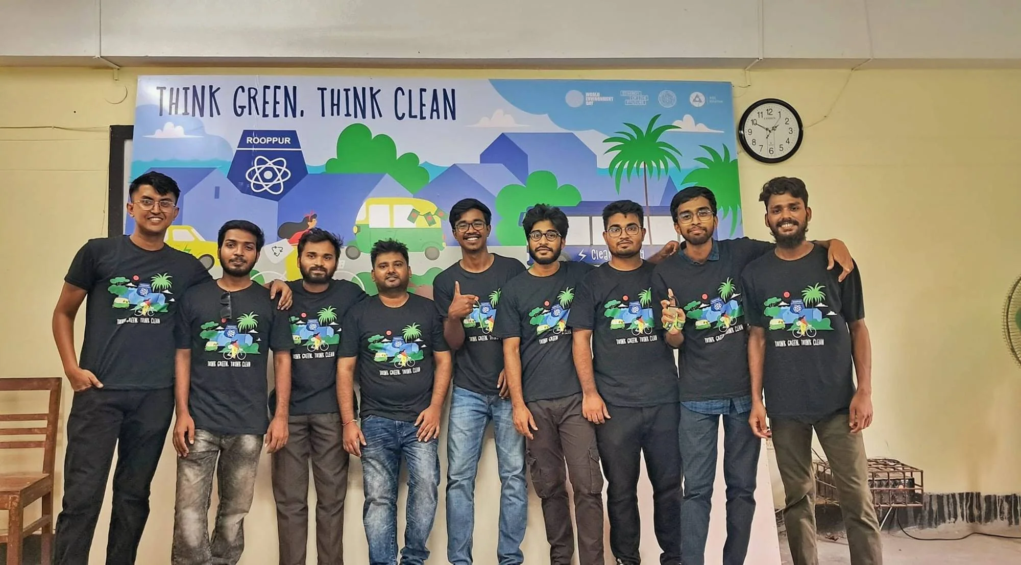 A group of young men in matching Think Green, Think Clean T-shirts in front of an illustrated banner